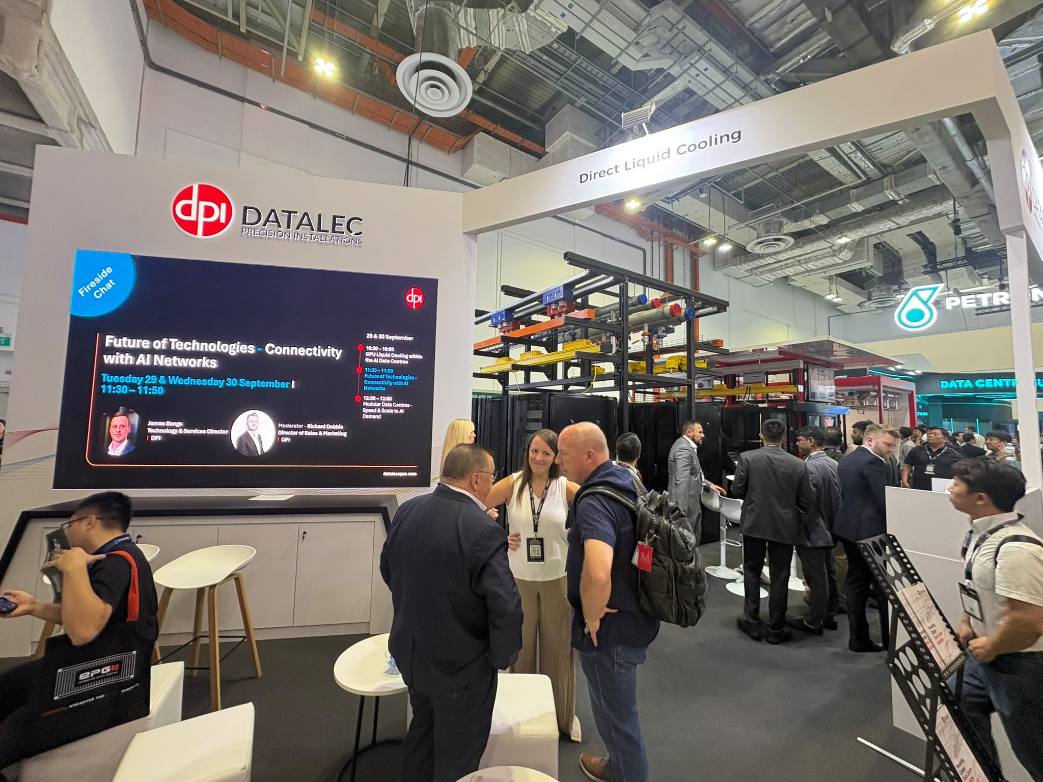 DPI Direct Liquid Cooling stand at DCW Asia 2026 with the fireside chat schedule on screen