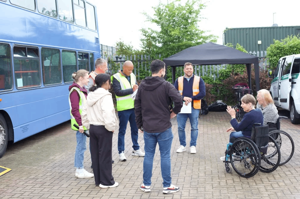 Group of diverse people standing around a blue London bus demonstrating accessibility